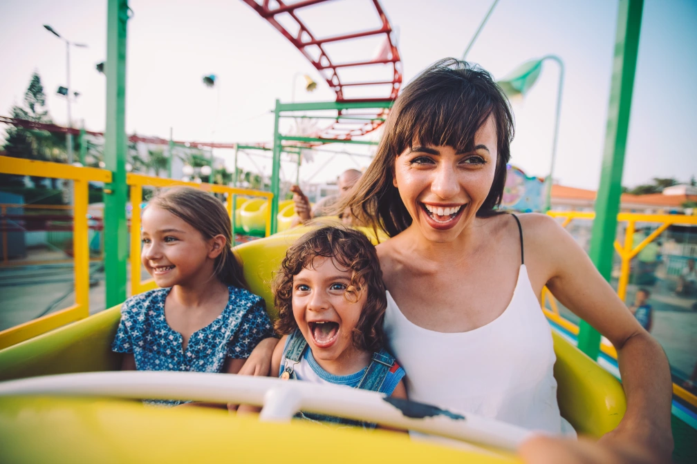 Little son and daughter with mother on roller coaster ride