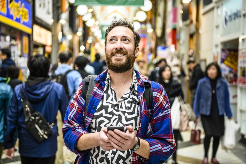 Portrait of tourist in patterned shirt looking up on busy street